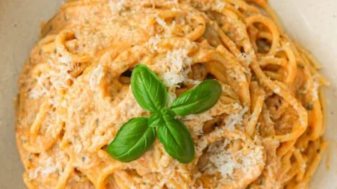 Dish of roasted tomato pasta with garlic ricotta, garnished with fresh herbs.